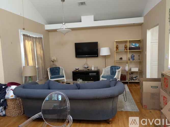 A living room with a grey sofa and a television on the wall.