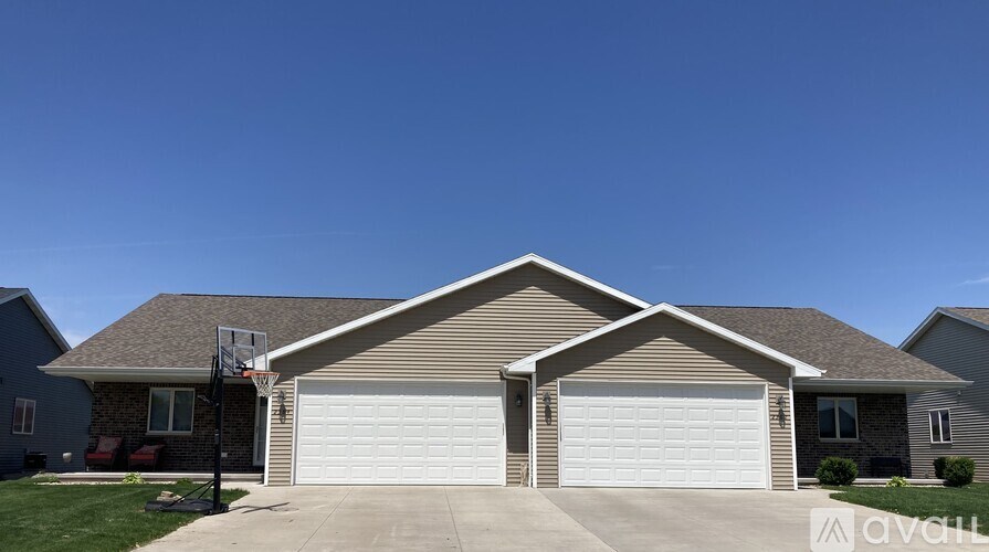 A house with a garage door and a basketball hoop.