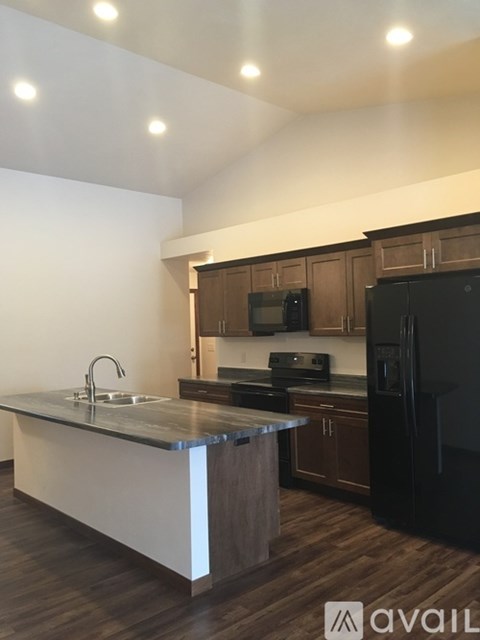 A kitchen with a black refrigerator and wooden cabinets.