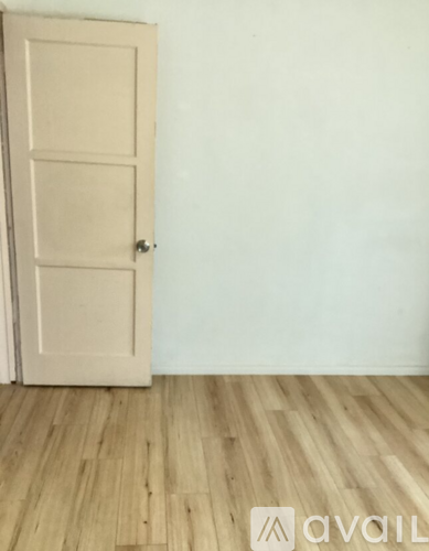 A wooden door with a handle is in a room with wooden flooring.
