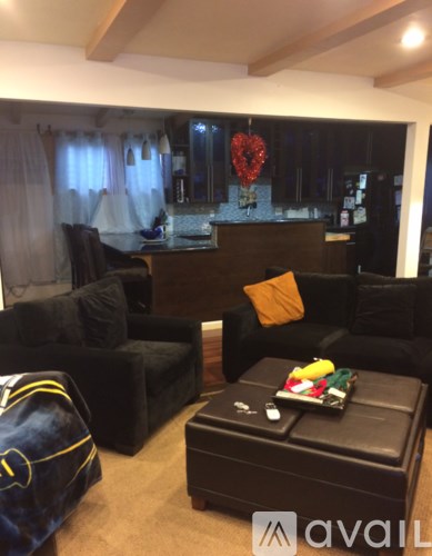 A living room with black furniture and a heart-shaped decoration hanging from the ceiling.