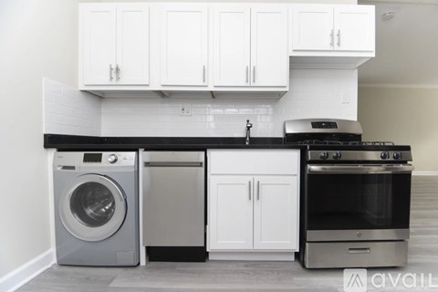 A modern kitchen with white cabinets and a black countertop.