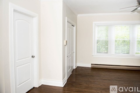 A room with a door, a window with blinds, and a ceiling fan.