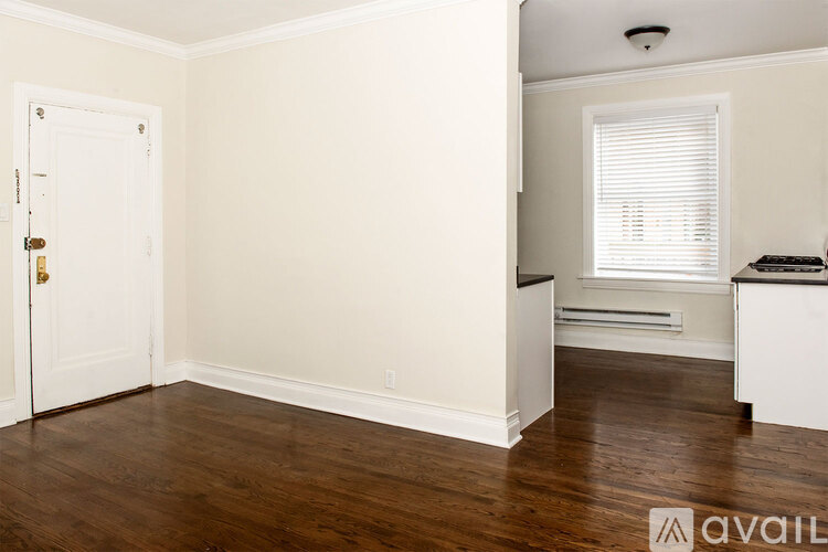 A spacious room with a ceiling fan and light, large windows, and a wooden floor.