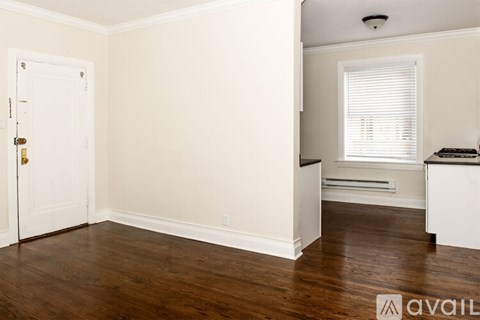 A spacious room with a ceiling fan and light, large windows, and a wooden floor.