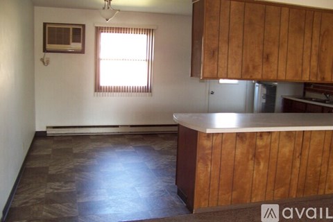 A kitchen with wooden cabinets and a window with blinds.