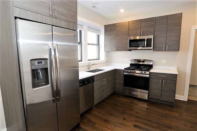 A modern kitchen with a stainless steel refrigerator and oven.