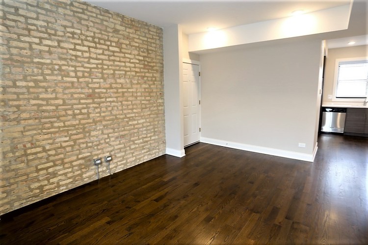 A room with a brick wall and wooden flooring.