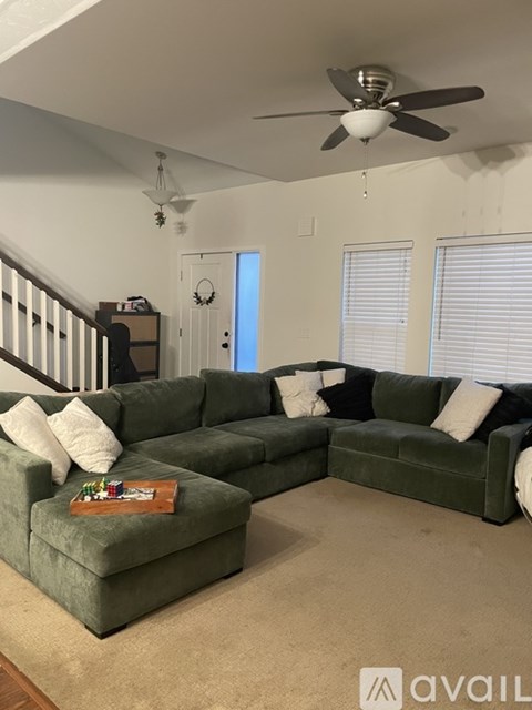A living room with a green couch and a ceiling fan.