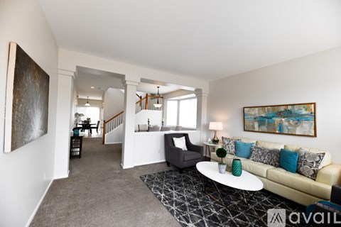 A living room with a white couch and a painting on the wall.