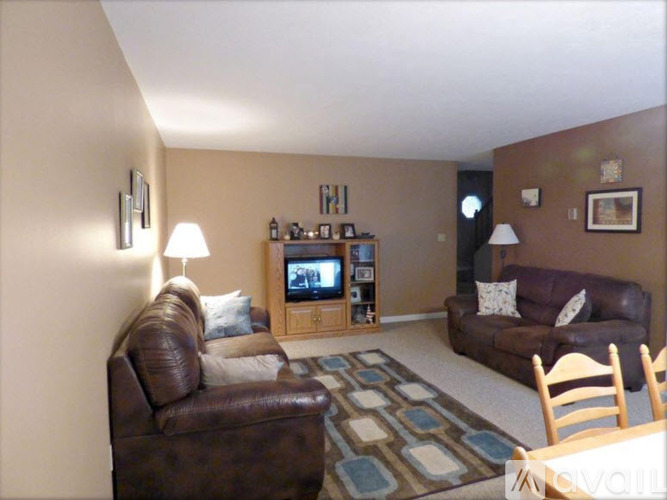 A living room with brown leather furniture and a television.