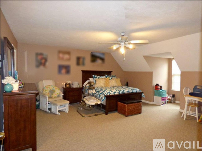 A bedroom with a bed, chair, and a ceiling fan.