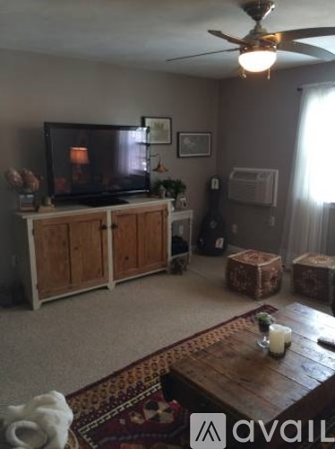 A living room with a television, a wooden cabinet, and a rug.