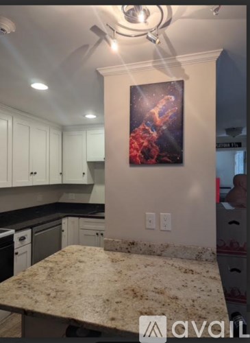 A kitchen with a marble countertop and a painting of a person on the wall.