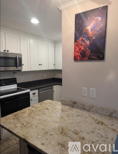 A kitchen with granite countertops and a painting of a nebula on the wall.