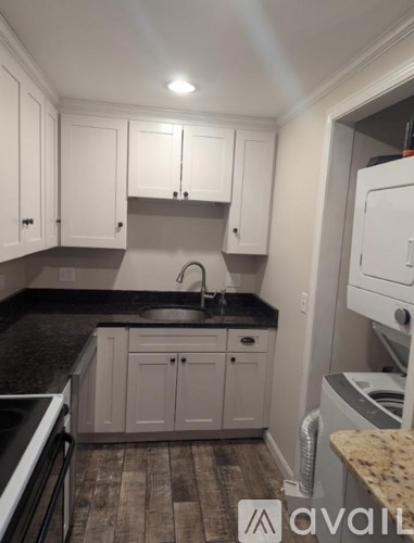 A kitchen with white cabinets and a black countertop.