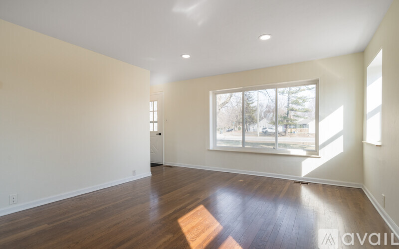 A spacious room with wooden floors and a large window.