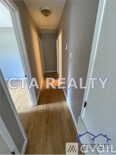 A room with wooden flooring and a wall with a switch and outlet.