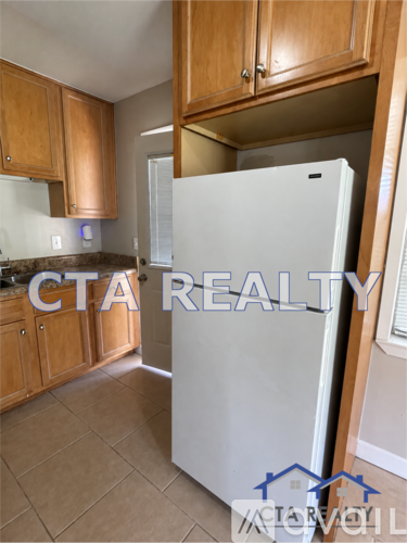 A white refrigerator in a kitchen with wooden cabinets.