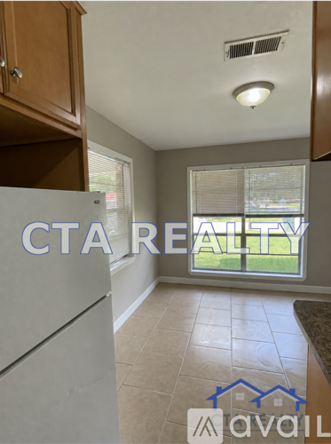 A kitchen with a refrigerator and a window with blinds.