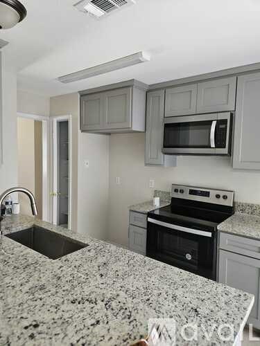 A kitchen with granite countertops and a stove top oven.