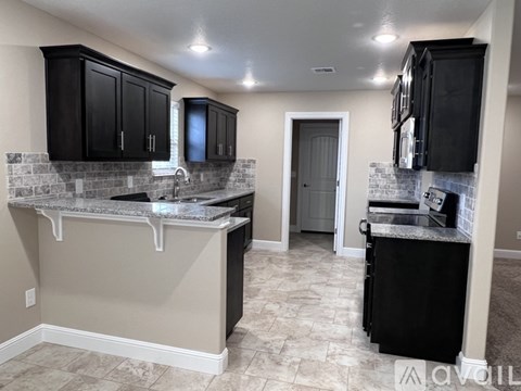 A kitchen with black cabinets and a tiled backsplash.