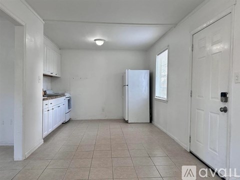 A kitchen with white cabinets and a white refrigerator.