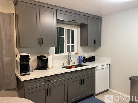 A kitchen with grey cabinets and a white countertop.