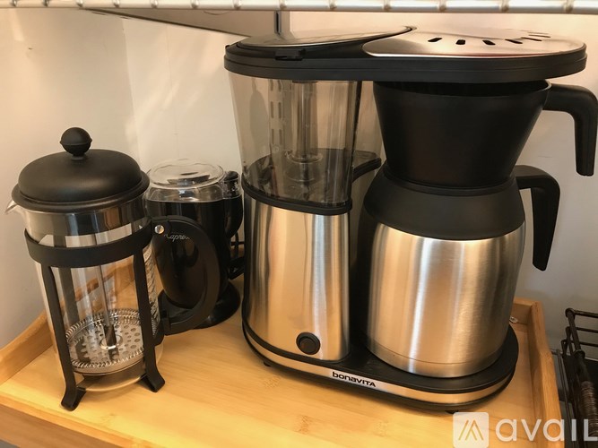 A coffee maker and a French press are on a wooden tray.