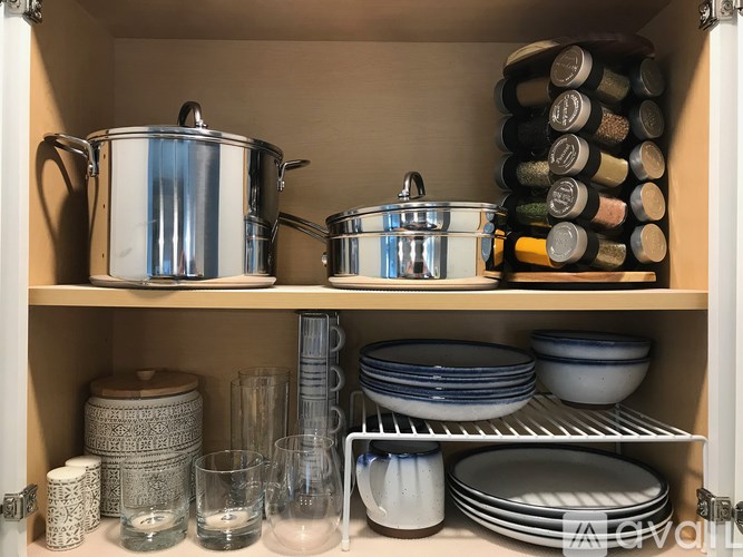 A kitchen cabinet is full of various dishes and cookware.