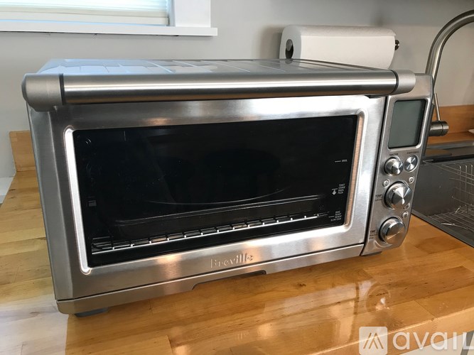A silver toaster oven with a black interior sits on a wooden countertop.