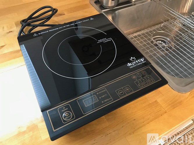A black induction cooktop with a power cord plugged in.