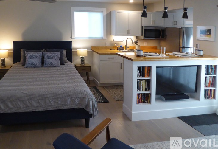 A bedroom with a bed, a kitchenette, and a television.
