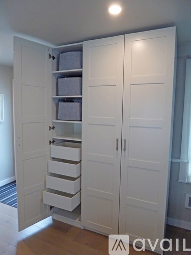 A white wardrobe with drawers and shelves is open.