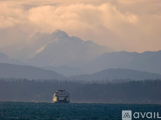 A large ship is sailing in the ocean near a mountain.
