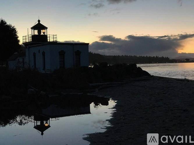 A lighthouse stands tall on the shore, its reflection visible in the calm water.