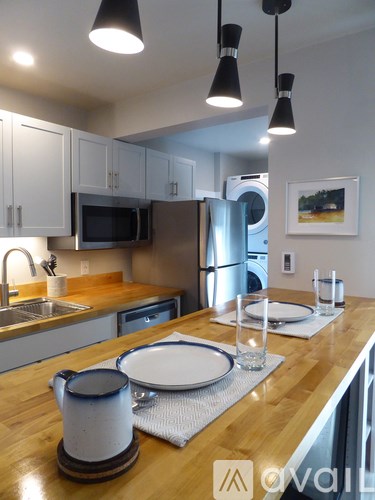 A kitchen with a wooden counter top and a white pitcher on it.