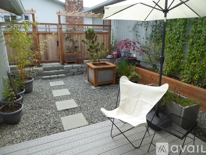 A patio with a white chair and a white umbrella.