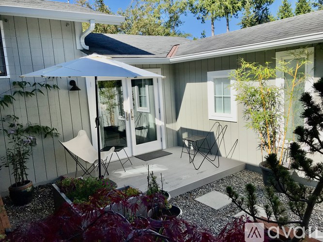 A patio with a white umbrella and chairs.