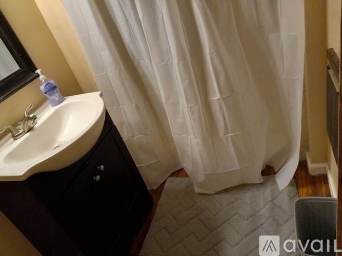A bathroom with a white sink and a white shower curtain.