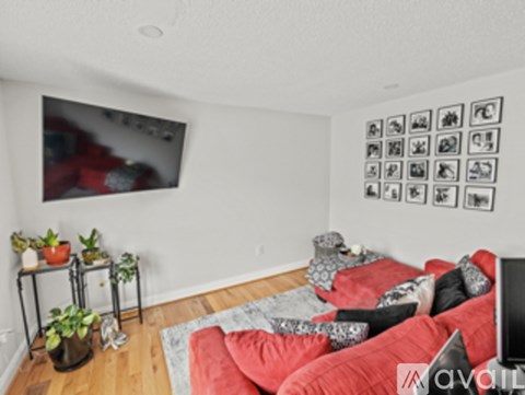 A living room with a red couch and a television on the wall.