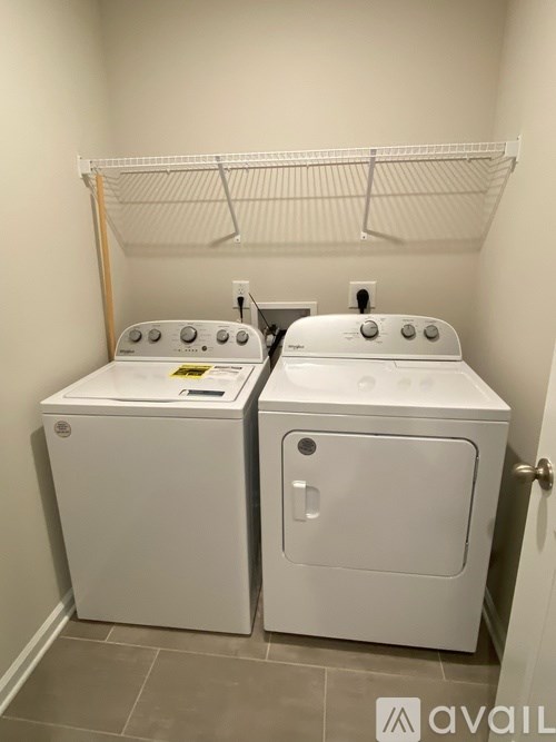 Two white front loading washing machines in a small laundry room.