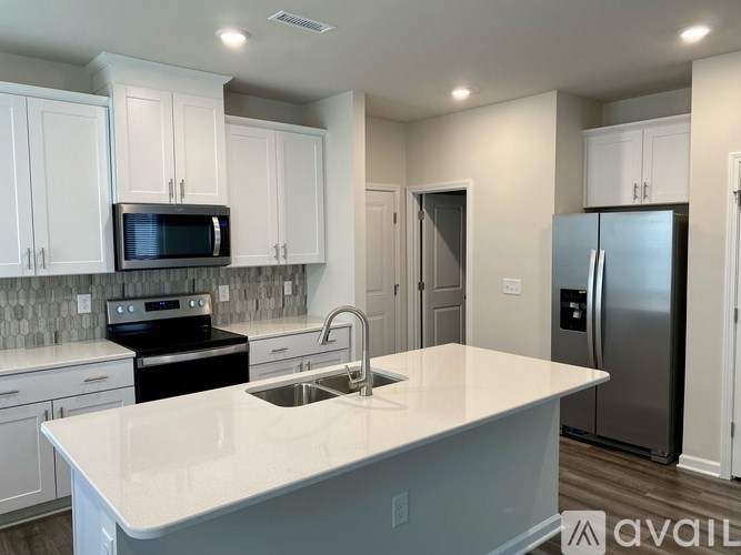 A kitchen with white cabinets and a white island.