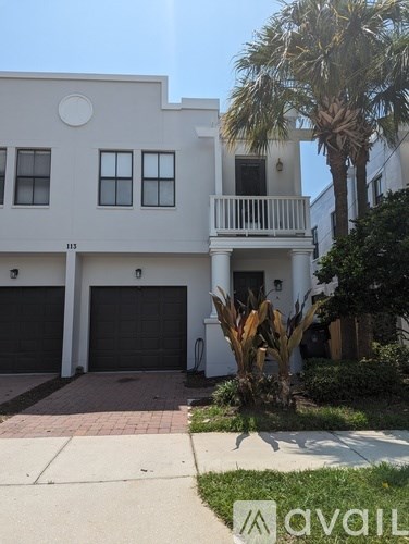 A white two-story house with a balcony and a garage.