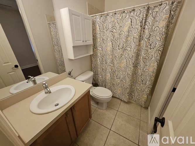 A bathroom with a sink, toilet and shower curtain.
