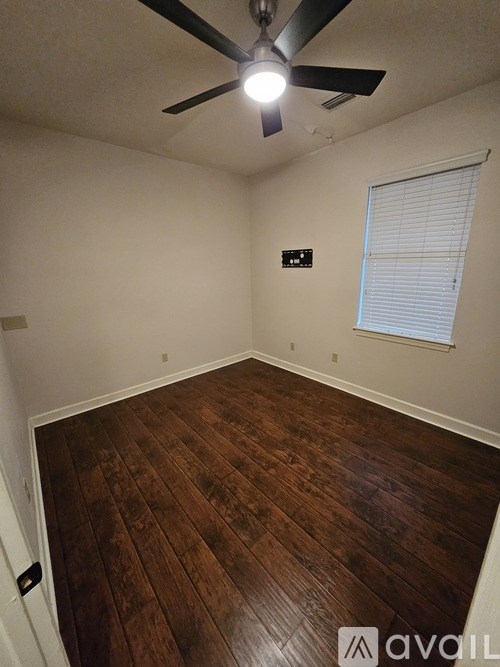 A room with wooden flooring and a ceiling fan.