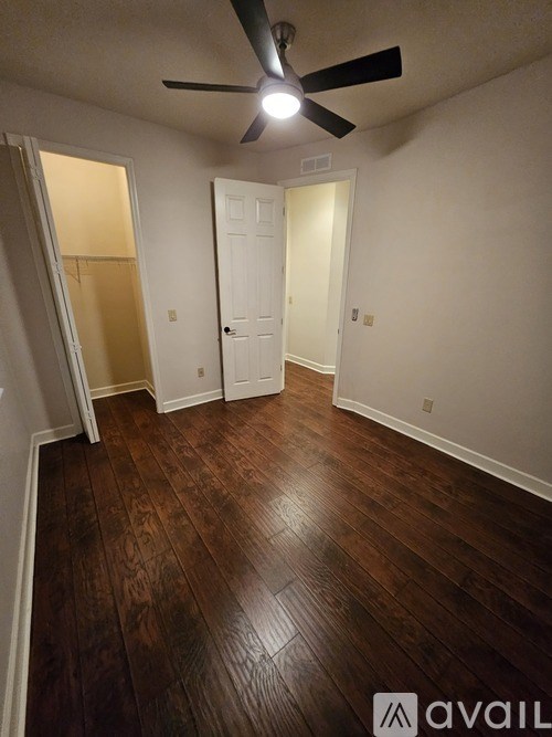 A room with a ceiling fan and wooden flooring.
