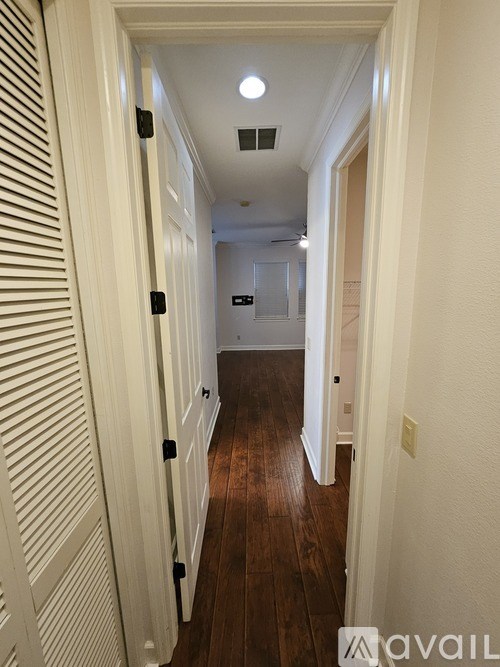A long hallway with white walls and wood floors.