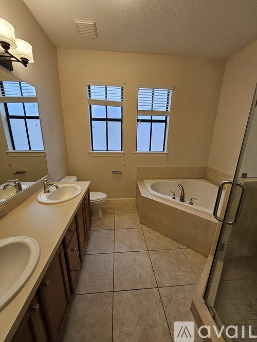 A bathroom with a tub, sink, toilet, and mirror.