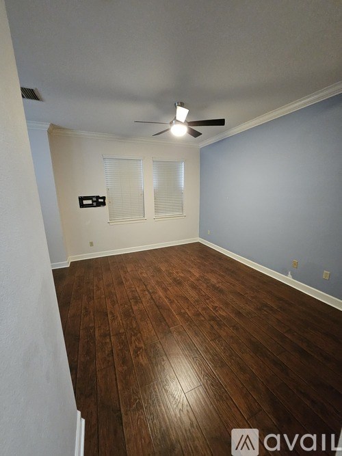 A room with wooden flooring and a ceiling fan.